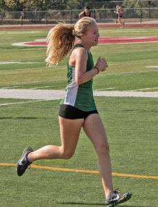 Athlete prepares for pole vault on a track with others watching.