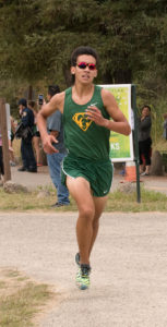 Athlete prepares for pole vault on a track with others watching.