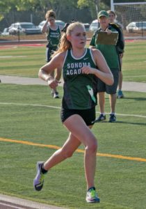 Athlete prepares for pole vault on a track with others watching.