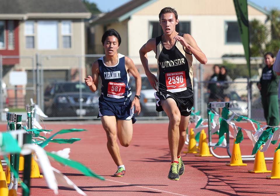 Athlete prepares for pole vault on a track with others watching.