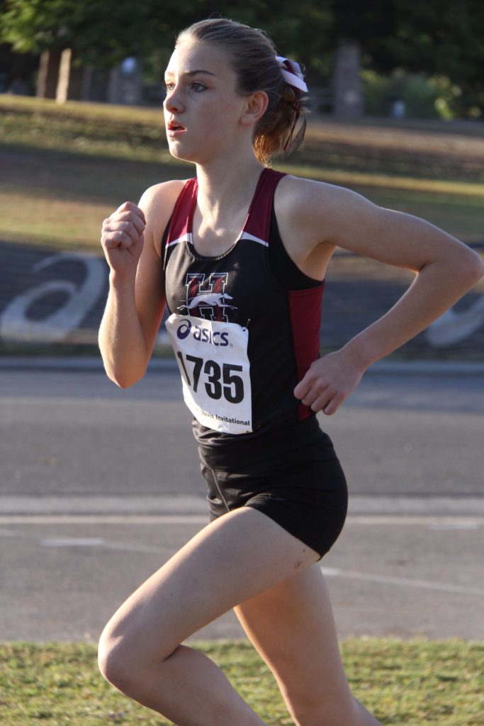 Athlete prepares for pole vault on a track with others watching.