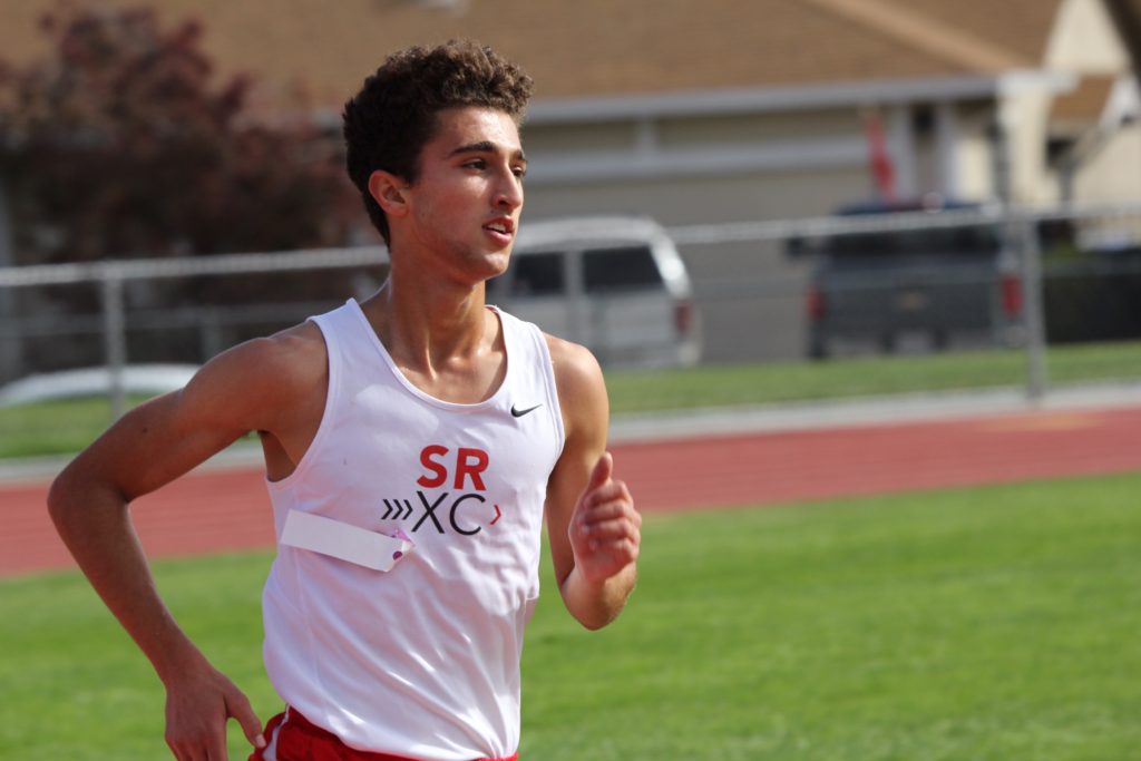 Athlete prepares for pole vault on a track with others watching.