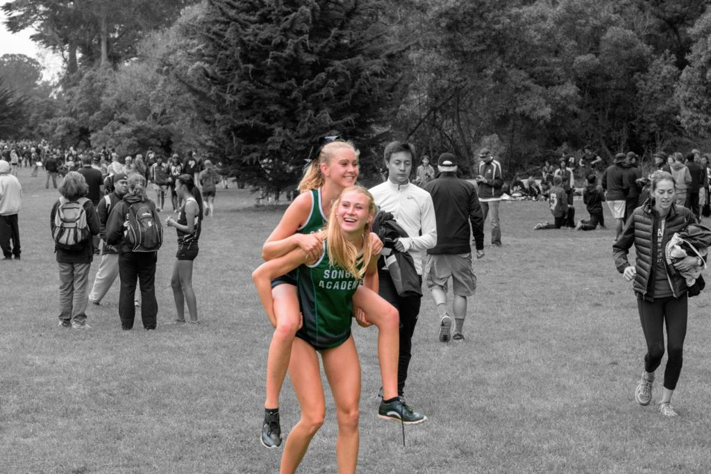 Athlete prepares for pole vault on a track with others watching.