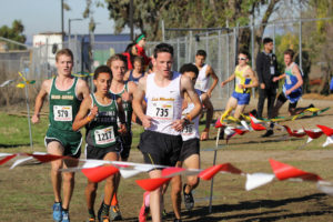 Athlete prepares for pole vault on a track with others watching.