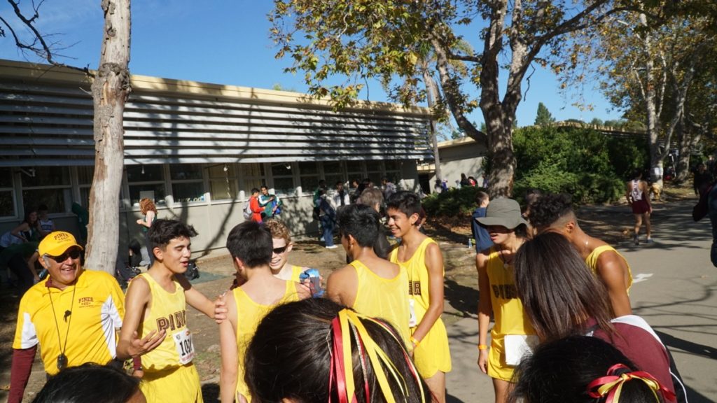 Athlete prepares for pole vault on a track with others watching.
