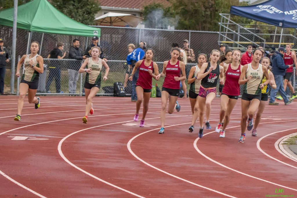 Athlete prepares for pole vault on a track with others watching.