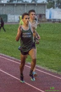 Athlete prepares for pole vault on a track with others watching.