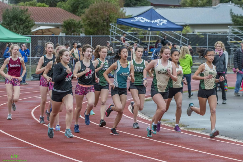 Athlete prepares for pole vault on a track with others watching.