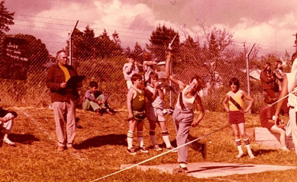 Athlete prepares for pole vault on a track with others watching.