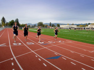 Athlete prepares for pole vault on a track with others watching.