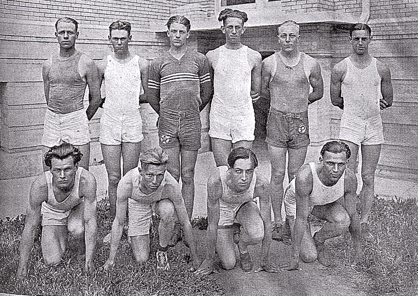 Athlete prepares for pole vault on a track with others watching.