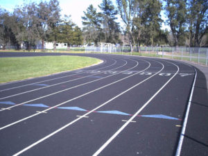 Athlete prepares for pole vault on a track with others watching.