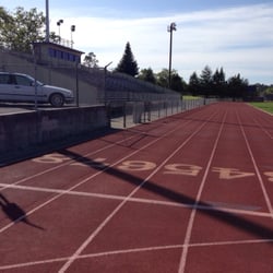 Athlete prepares for pole vault on a track with others watching.