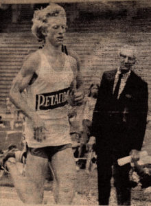 Athlete prepares for pole vault on a track with others watching.