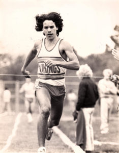 Athlete prepares for pole vault on a track with others watching.