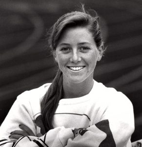 Athlete prepares for pole vault on a track with others watching.
