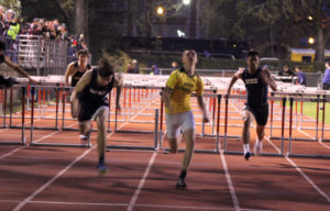 Athlete prepares for pole vault on a track with others watching.