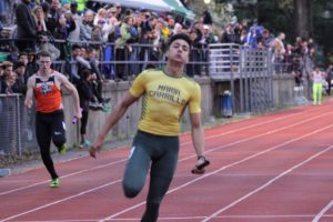 Athlete prepares for pole vault on a track with others watching.
