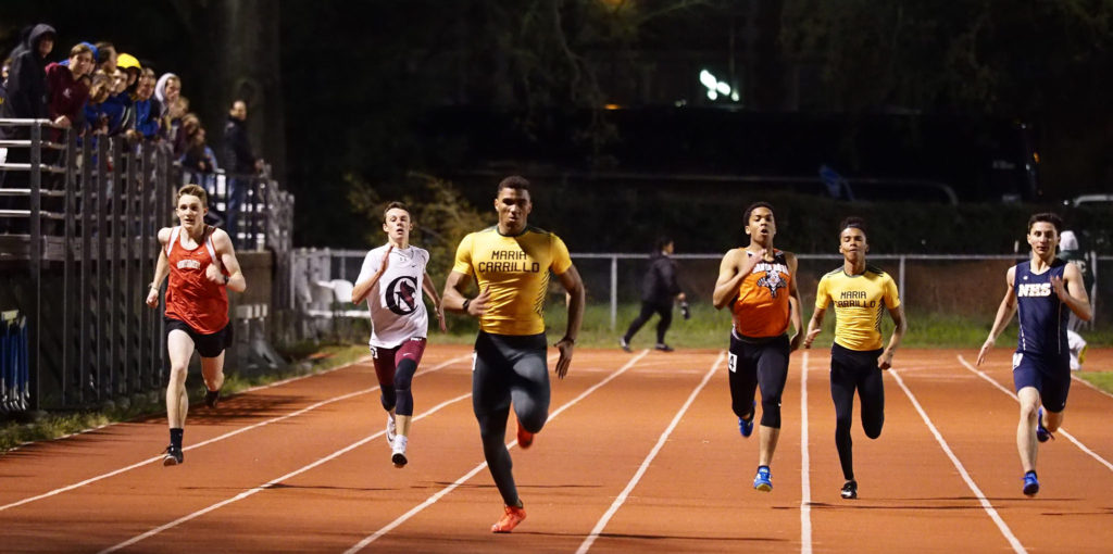 Athlete prepares for pole vault on a track with others watching.