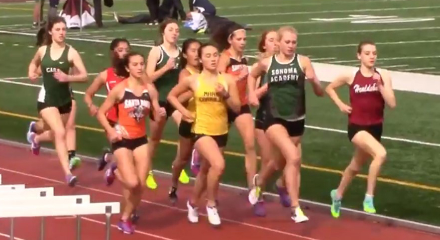Athlete prepares for pole vault on a track with others watching.