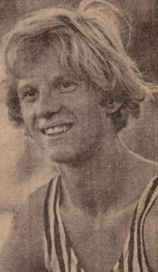 Athlete prepares for pole vault on a track with others watching.