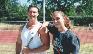 Athlete prepares for pole vault on a track with others watching.