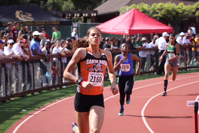 Athlete prepares for pole vault on a track with others watching.