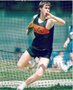 Athlete prepares for pole vault on a track with others watching.