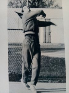 Athlete prepares for pole vault on a track with others watching.