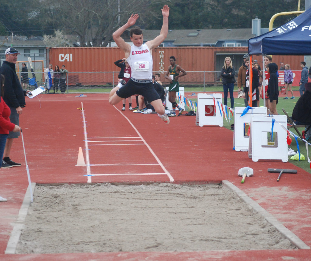 Athlete prepares for pole vault on a track with others watching.