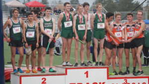 Athlete prepares for pole vault on a track with others watching.