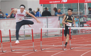 Athlete prepares for pole vault on a track with others watching.