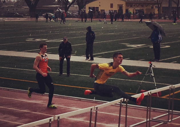Athlete prepares for pole vault on a track with others watching.