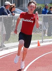 Athlete prepares for pole vault on a track with others watching.