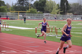 Athlete prepares for pole vault on a track with others watching.