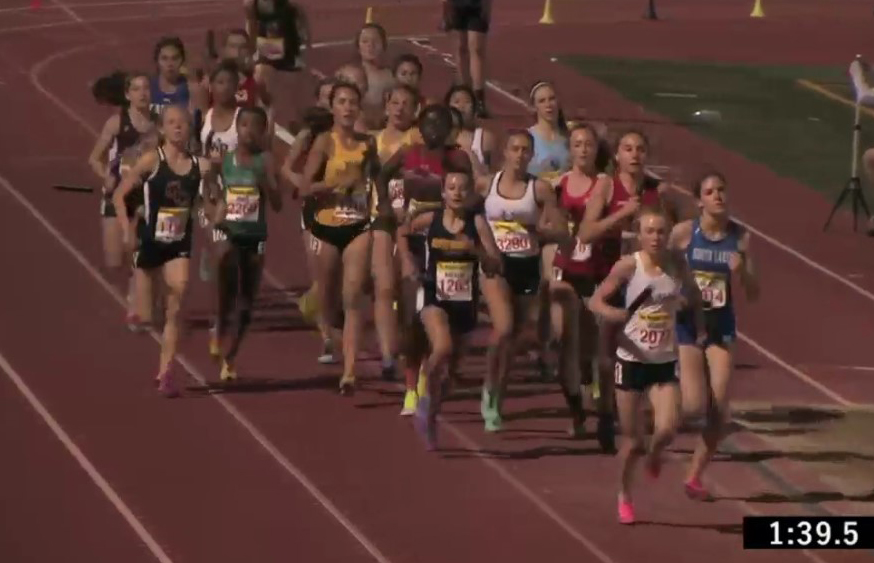 Athlete prepares for pole vault on a track with others watching.