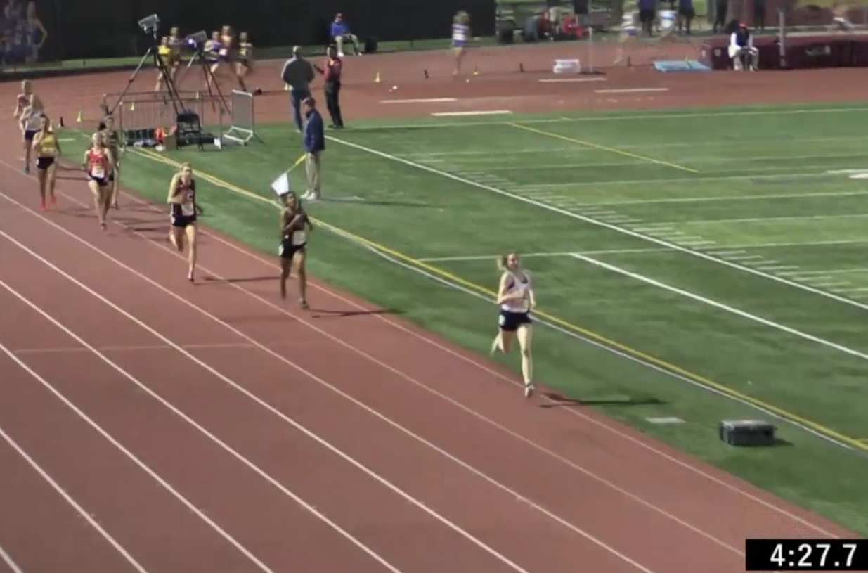 Athlete prepares for pole vault on a track with others watching.