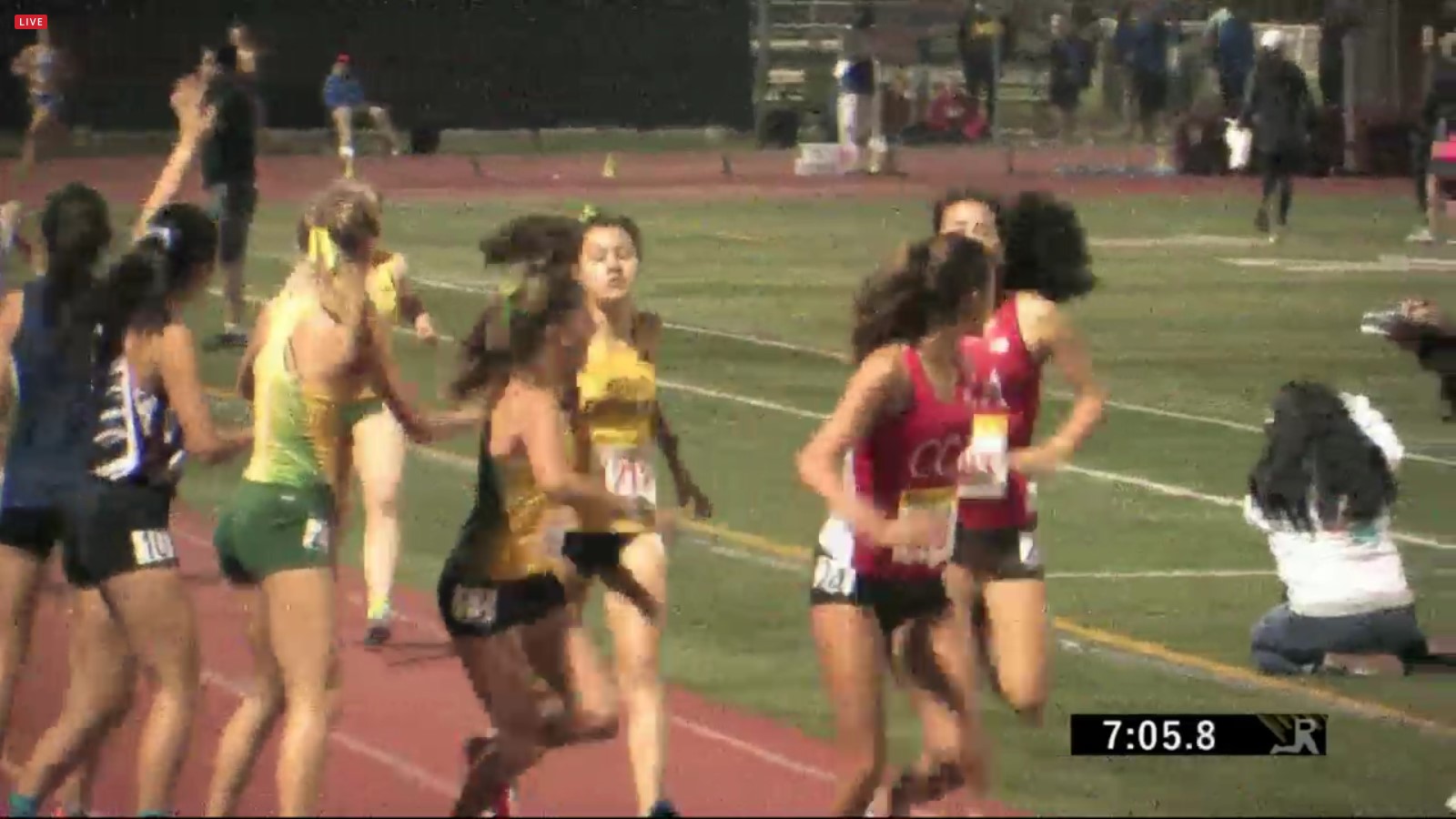Athlete prepares for pole vault on a track with others watching.