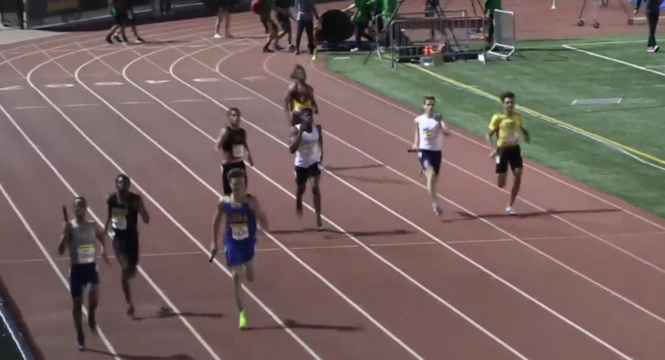 Athlete prepares for pole vault on a track with others watching.