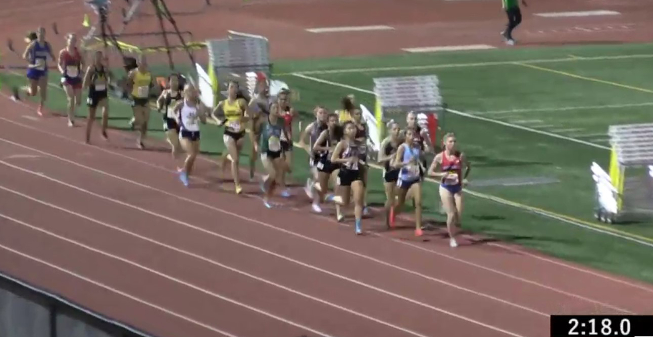 Athlete prepares for pole vault on a track with others watching.