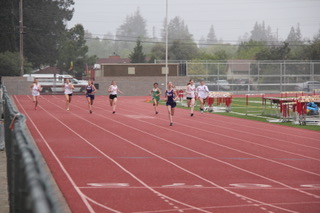 Athlete prepares for pole vault on a track with others watching.