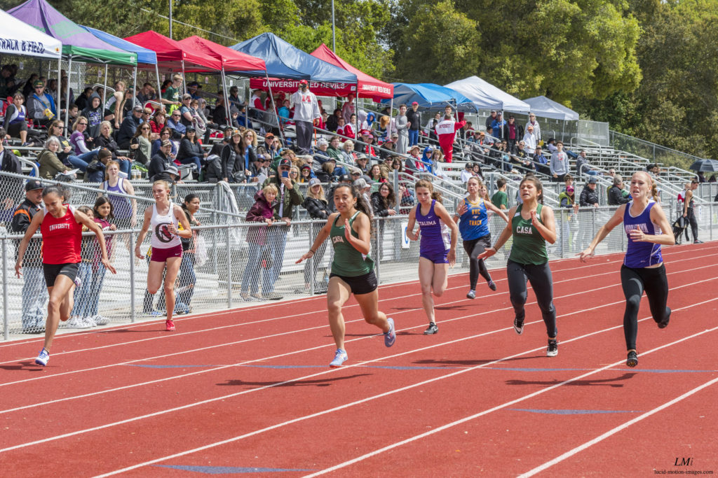 Athlete prepares for pole vault on a track with others watching.