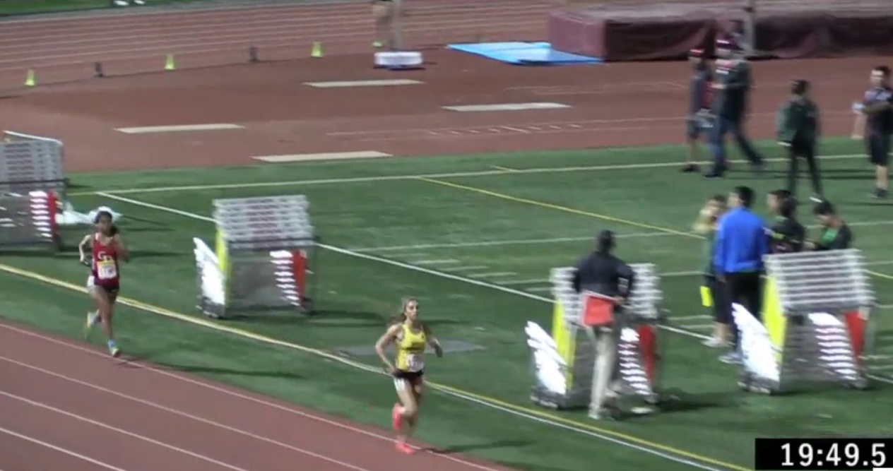 Athlete prepares for pole vault on a track with others watching.