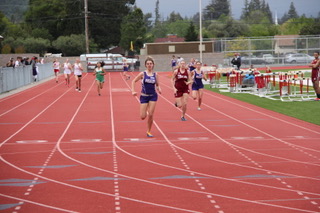 Athlete prepares for pole vault on a track with others watching.