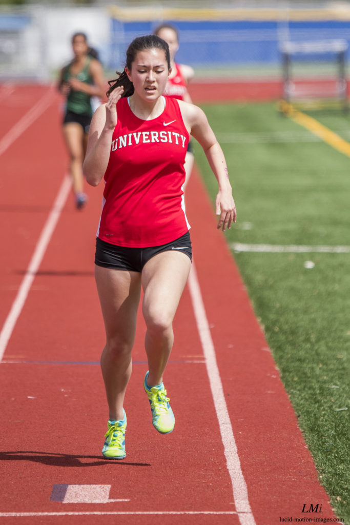 Athlete prepares for pole vault on a track with others watching.