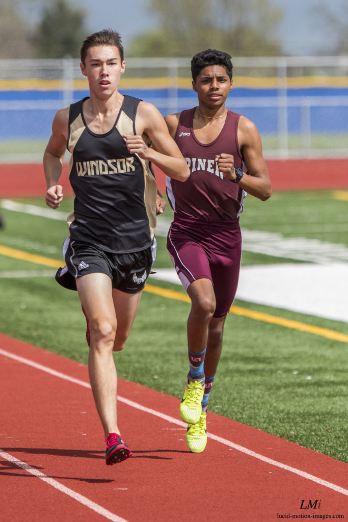 Athlete prepares for pole vault on a track with others watching.