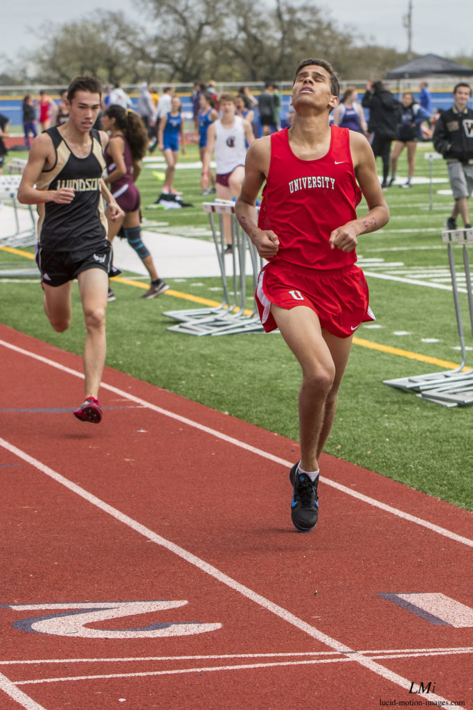 Athlete prepares for pole vault on a track with others watching.
