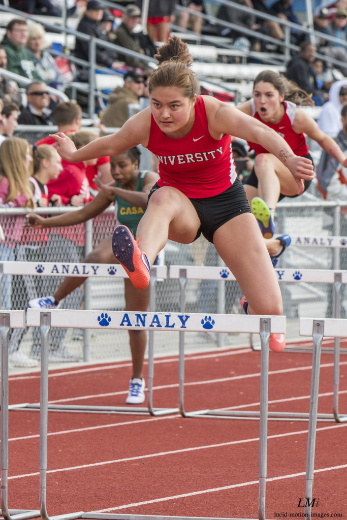 Athlete prepares for pole vault on a track with others watching.