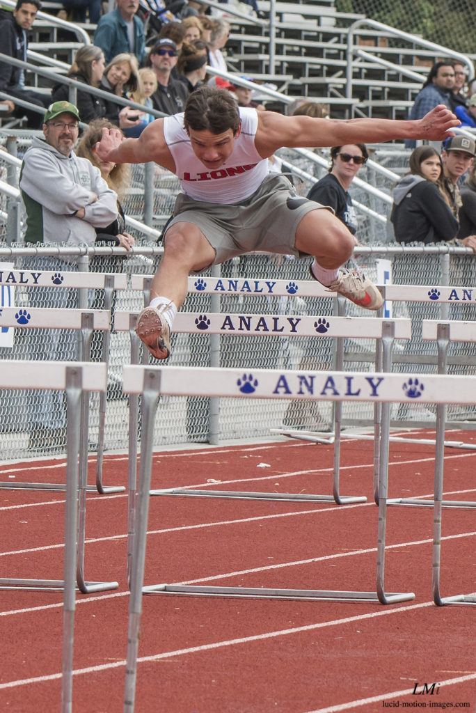 Athlete prepares for pole vault on a track with others watching.