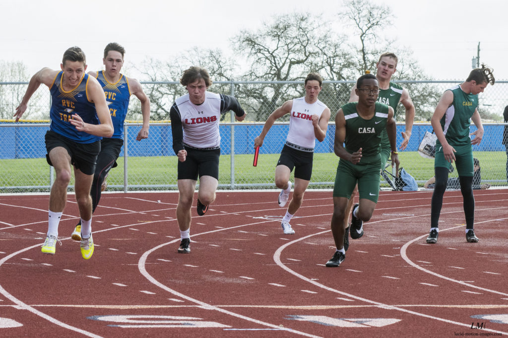 Athlete prepares for pole vault on a track with others watching.